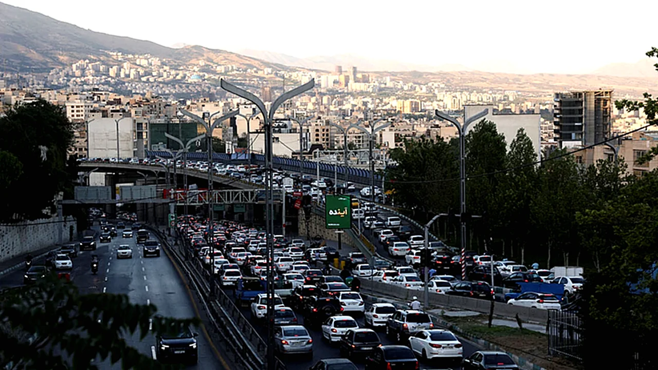 إيرانيون يشككون تحسن سيارات في طهران خلال ازدحام مروري ضمن
